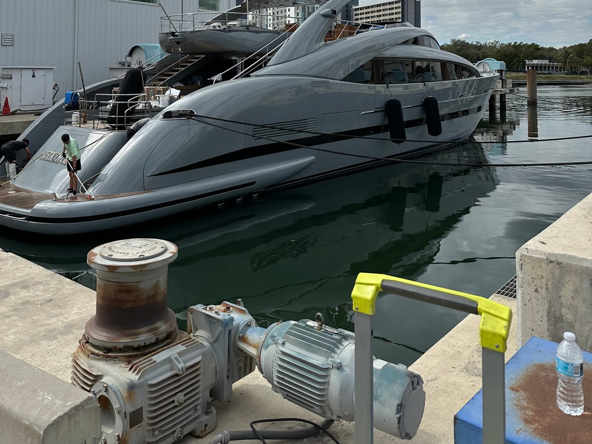 Gray motor yacht being finished alongside a dock